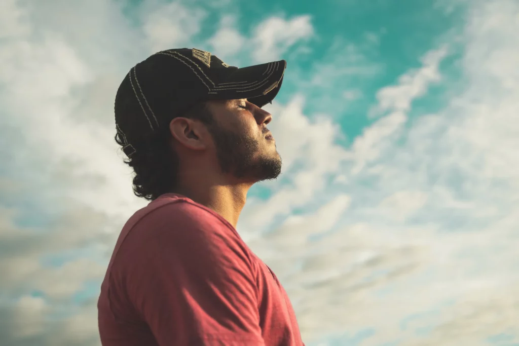 man breathing outside under the clouds